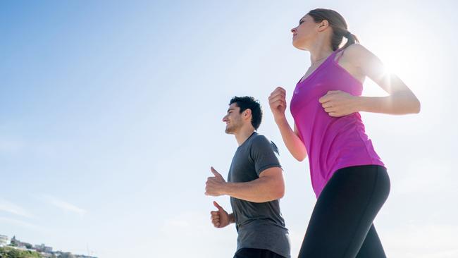 Fit couple of people running at the beach and looking happy exercising