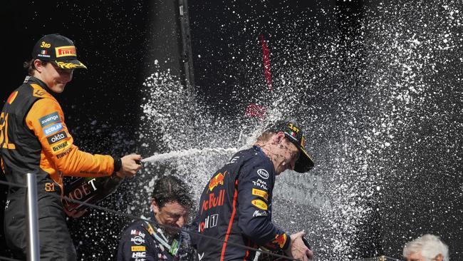 Oscar Piastri of Australia sprays first-placed Red Bull driver Max Verstappen. Picture: AP Photo/Antonio Calanni