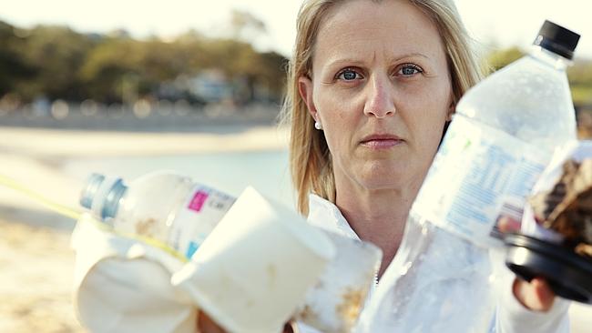 Lynn Mann collects discarded drinks containers on Sydney’s Balmoral Beach. Picture: Braden Fastier