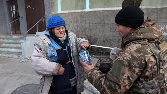 A Ukrainian serviceman gives food and water to a local elderly woman in besieged Bakhmut. Picture: Anatolii Stepanov / AFP