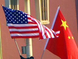 Worker installs the US (L) flag next to the flag of China in front of the portrait of late communist leader Mao Zedong for vi...