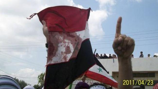 Syrian anti-government protesters hold a bloodied national flag during a funeral procession for slain activists in Izraa, Syria, in April 2011. Picture: AP