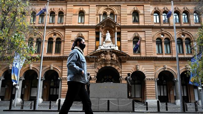 A woman wearing a face mask walks through a quiet Martin Place in Sydney. Picture: AFP