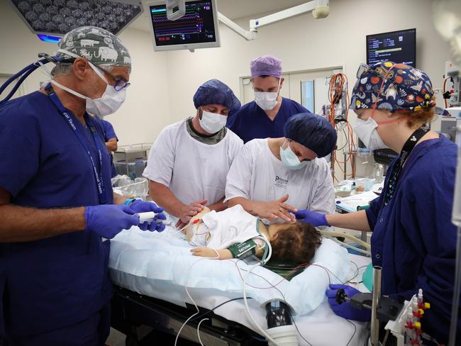 Parents Kristy and Matt Busuttil comfort Harlen as he went under for the transplant with the anaesthesia team. Picture: David Caird