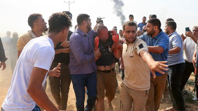 Palestinians lead a reportedly captured and injured Israeli man in the southern Gaza Strip. Picture: AFP