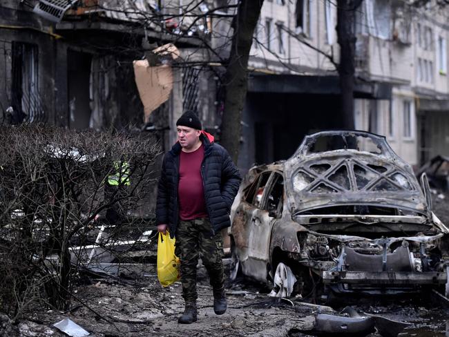 A man walks by destroyed cars next to a damaged residential building following a missile strike in Kyiv. Picture: AFP