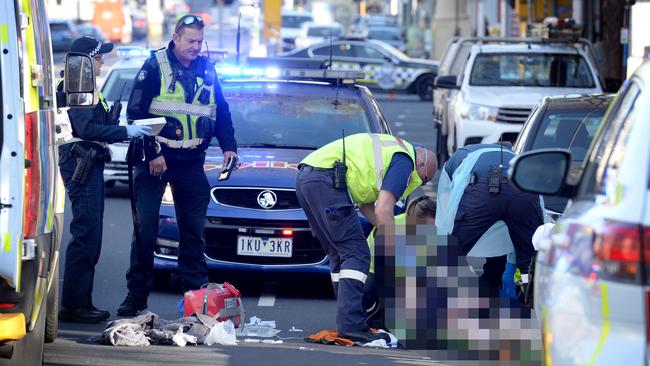 Paramedics tend to an injured man after he was struck by a car on Bridge Rd, Richmond. Picture: Andrew Henshaw