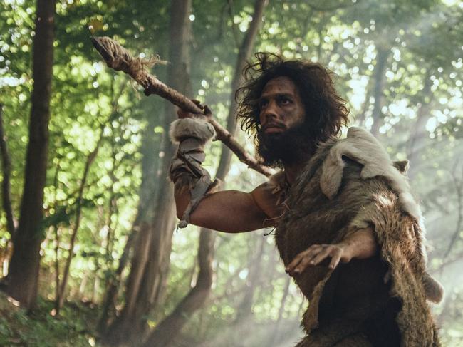 Primeval Caveman Wearing Animal Skin Holds Stone Tipped Spear Looks Around, Explores Prehistoric Forest in a Hunt for Animal Prey. Neanderthal Going Hunting in the Jungle