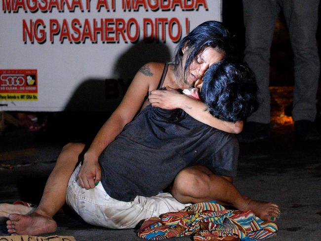 Jennilyn Olayres hugs the body of her partner Michael Siaron who was killed by an unidentified gunman and left with a cardboard sign with a message "I'm a pusher". Picture: AFP