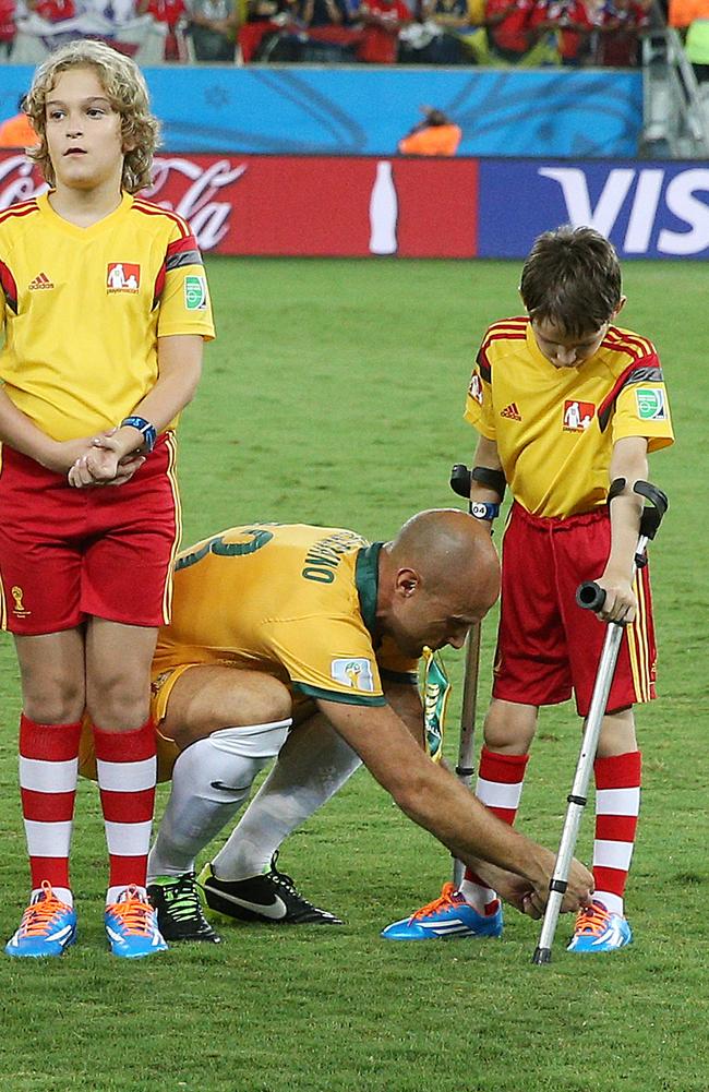 This image of Mark Bresciano tying up a young mascot’s shoelaces has gone viral. Picture: George Salpigtidis