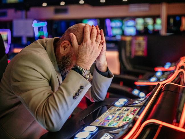 Senior men using slot machine to gamble in night club, having difficulties to make money, he is losing