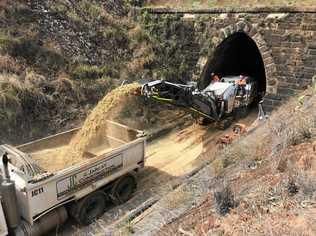 Workers dredging gravel and sand to lower and widen an old train tunnel along the range to make them large enough to handle modern contain freight. Picture: TMR