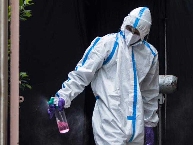 A health official wearing a Personal Protective Equipment (PPE) suit sprays disinfectant at the entrance of a temporary testing facility after authorities eased restrictions imposed as a preventive measure against the spread of the COVID-19 coronavirus, in New Delhi on July 8, 2020. - Hospitals in densely populated cities such as Mumbai and Delhi are struggling to cope with the epidemic, and the country now has around 720,000 infections -- the world's third-highest. (Photo by XAVIER GALIANA / AFP)