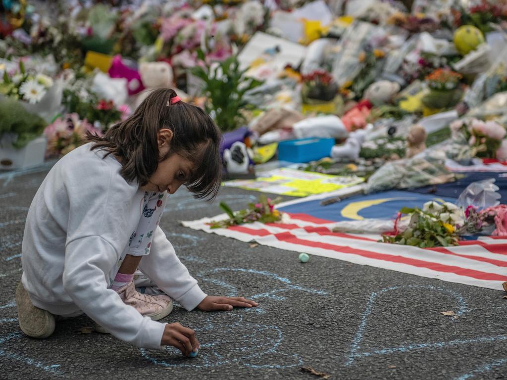 A young girl writes a message on the ground with chalk next to flowers and tributes near Al Noor mosque. picture: Getty Images