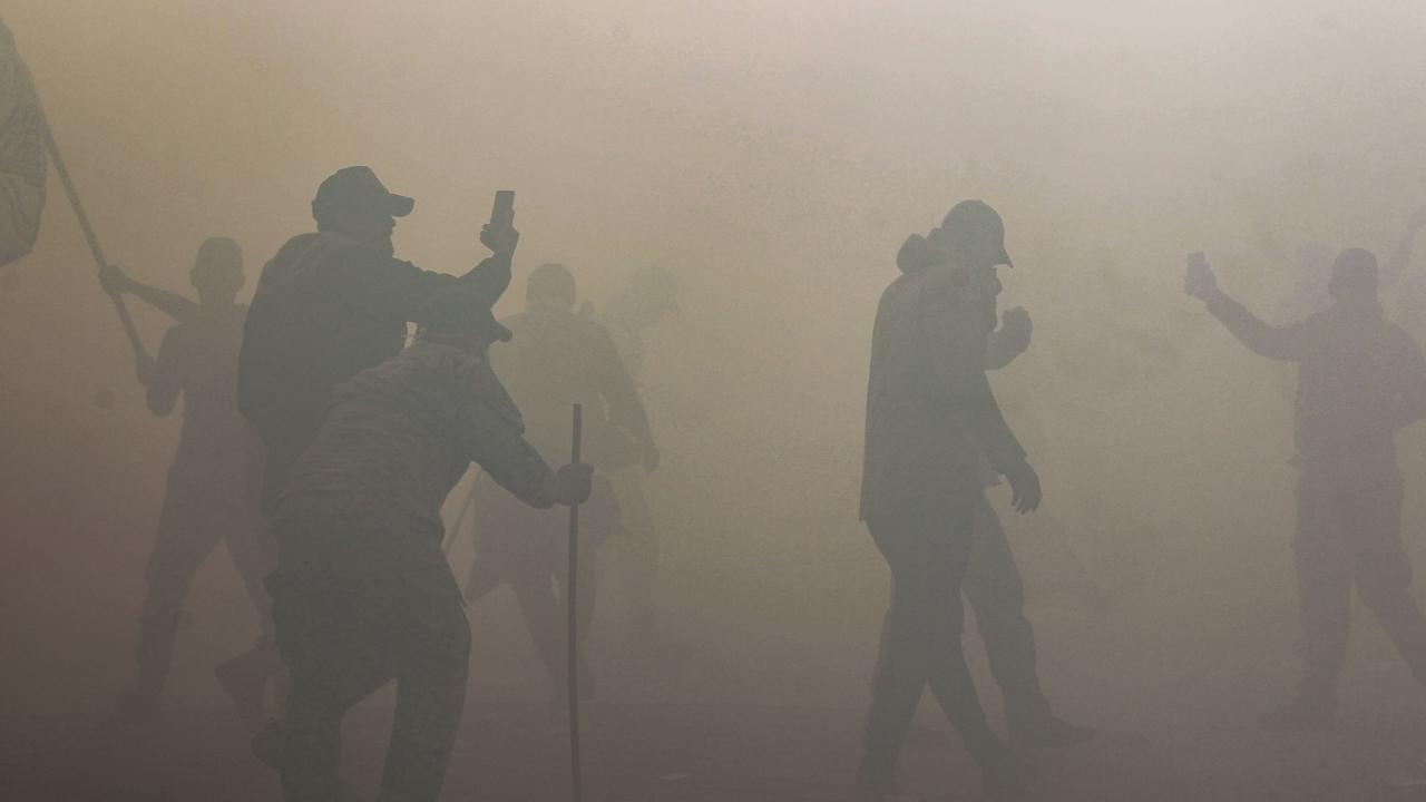 Iraqi supporters and members of the Hashed al-Shaabi military network can be seen through thick tear gas. Picture: Ahmad Al-Rubaye/AFP