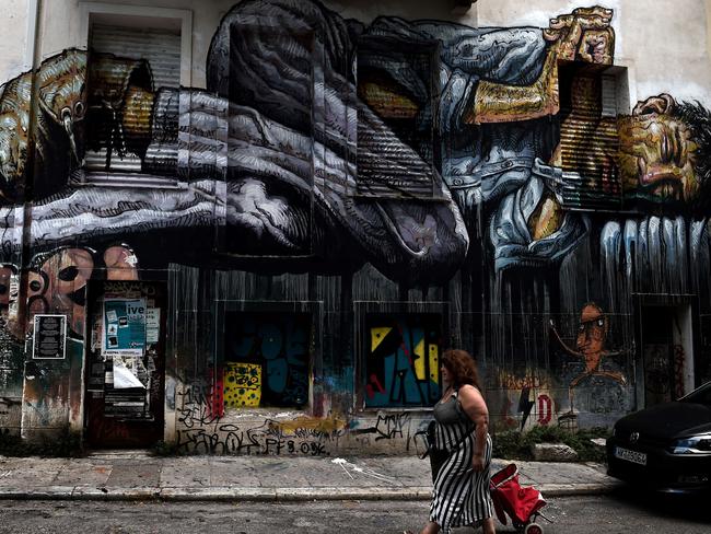 Tragic scenes ... graffiti depicting a homeless person is scrawled on a building in central Athens. Picture: AFP/Aris Messinis