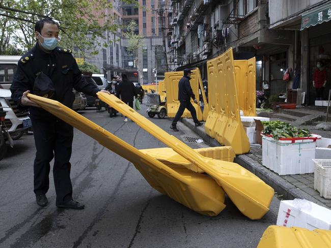 A city worker removes barriers used to seal off a community as the city of Wuhan prepares for the end of lockdown. Picture: AP