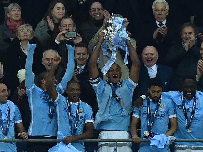 Manchester City's Belgian defender Vincent Kompany (C) holds up the English League Cup .