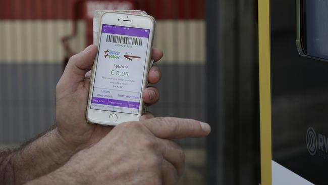 A man holds his mobile phone bearing an application showing the credit earned after inserting a plastic bottle into an automatic recycling bin outside a subway station in Rome, Wednesday, July 24, 2019. Rome unveiled Tuesday three test machines around metro stations where passengers can drop plastic water bottles, receiving five cents apiece, which goes to the passengerâ€™s account in partner apps to be redeemed for public transportation tickets. (AP Photo/Gregorio Borgia)