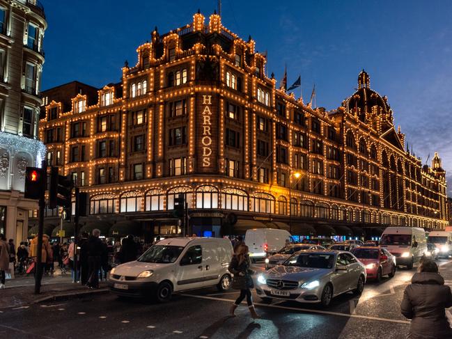 ESCAPE: London, UK - Pedestrians and traffic on the street in front of the illuminated facade of Harrods Department Store in Kensington. Picture: Istock