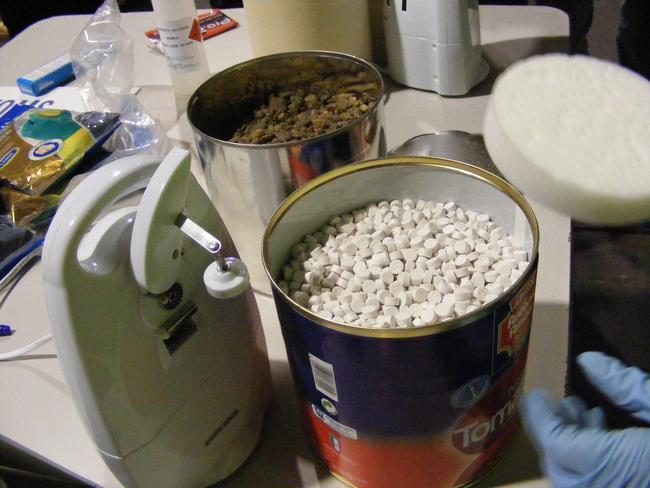 Agents opening the tins to reveal the huge haul of pills.