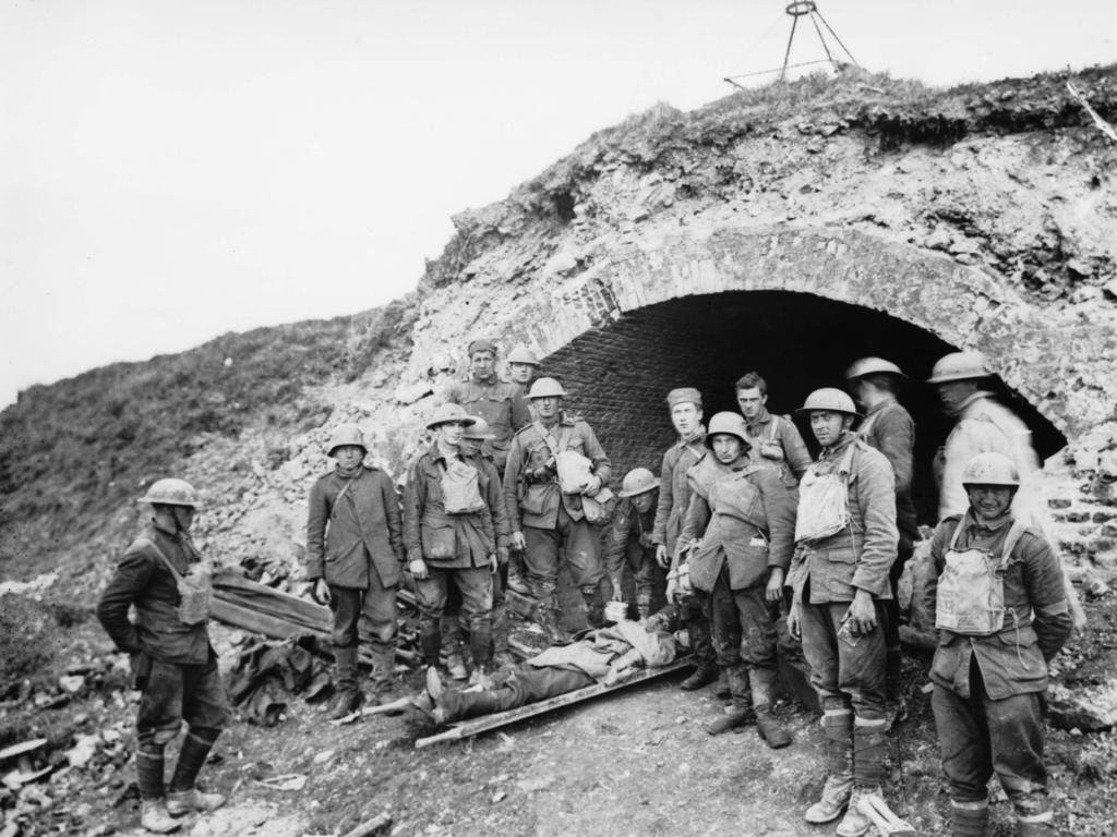 German prisoners resting with a wounded comrade at one of the access entrances to the St Quentin Canal Tunnel, in the captured Hindenburg Defence System. MUST CREDIT Australian War Memorial