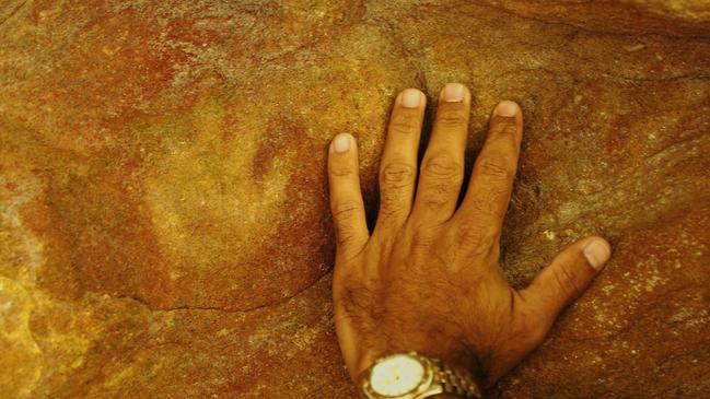 Aboriginal Heritage Conservation Officer Mark Simon shows the size of an infants hand print in a cave in the Blue Mountains. Picture: DAVID HILL