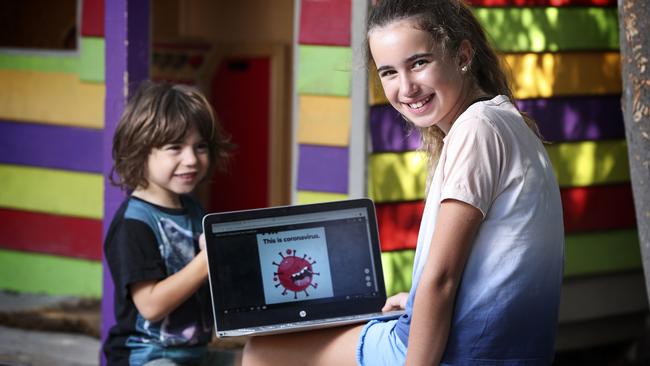 Sienna, 10, reading the book Hi. This is coronavirus to her younger brother Archer. Picture: Sarah Reed