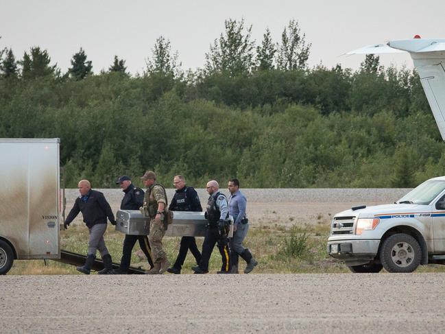 Mantioba RCMP officers offload the first of two metal boxes with the remains of the triple murder suspects on their way to Winnipeg for an autopsy. Picture: Twitter