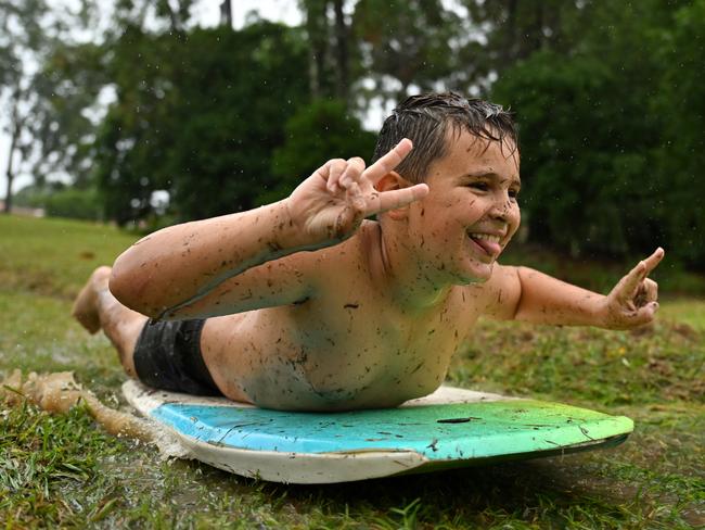 A boy taking advantage of the wet weather and sliding down a mud hill in the suburb of Upper Kedron in Brisbane on Saturday. Picture: Albert Perez/Getty Images