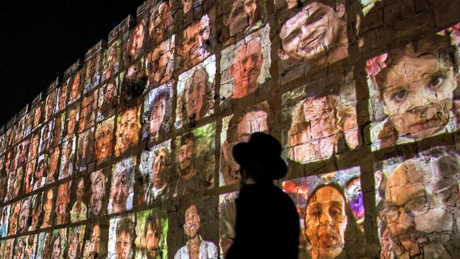 A man walks outside the walls of the old city of Jerusalem, on which are projected pictures of the hostages abducted by Palestinian militants on the October 7. Picture: AFP