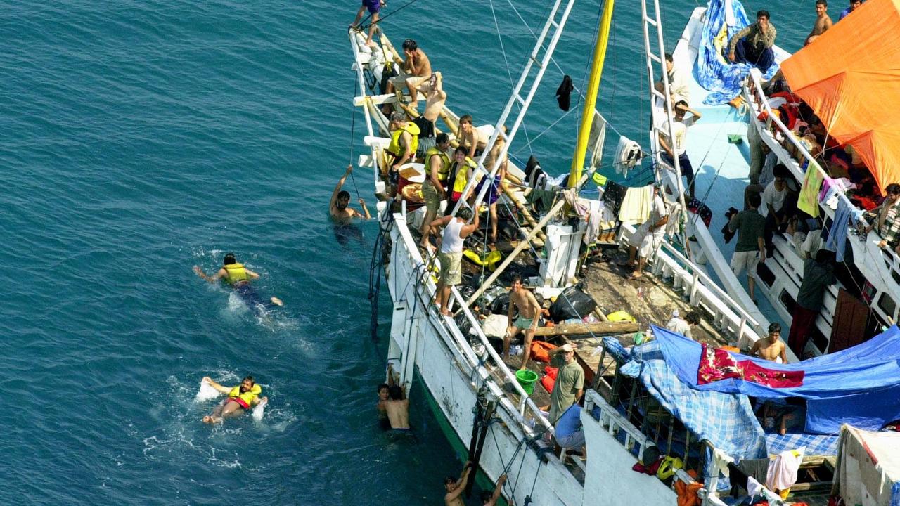 Asylum-seeking refugees swim around two of three refugee boats anchored at Ashmore Reef off Australia’s north coast in 2001. Picture: Megan Lewis