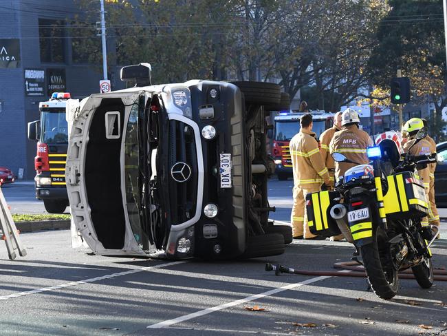 Metropolitan Firefighters attend to a Victorian Ambulance rollover on the corner of Queensbury and Peel street in North Melbourne. Picture: AAP/James Ross