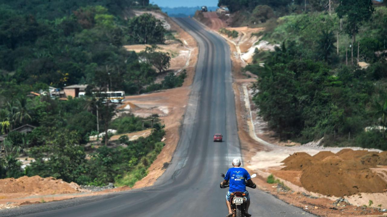 A motorcycle rides along the Trans-Amazonian highway (BR230) near Ruropolis. The route has played a key part in opening up once impenetrable parts of the Amazon, but at what cost? (Photo by Nelson Almeida/ AFP)