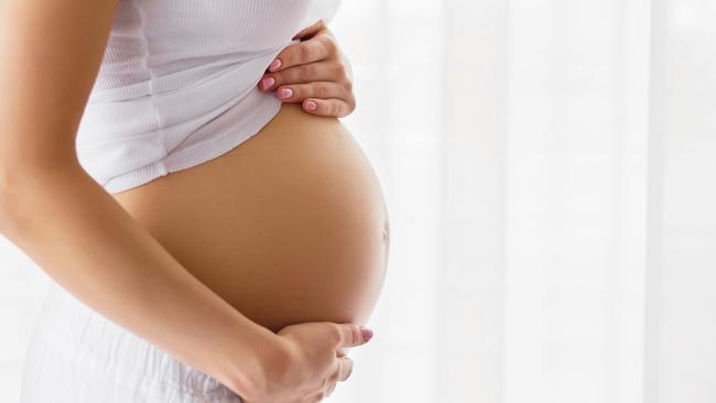 Pregnant woman standing next to window