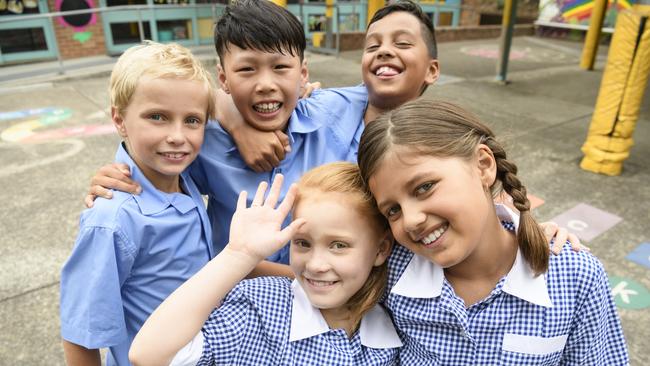 Two girls and three boys wearing school uniform smiling towards camera