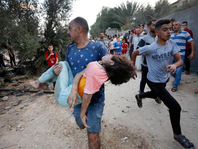 A Palestinian man carrying a young Palestinian girl after she was rescued from under the rubble of a home following an Israeli attack on the town of Deir Al-Balah, in the central Gaza Strip. Picture: AFP