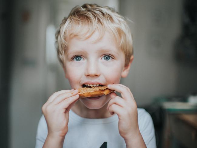 Sweet kid eating a bagel with peanut butter