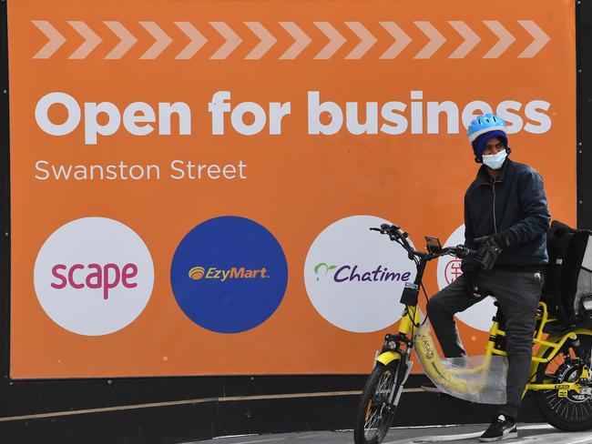 A food delivery worker waits to cross the street in Melbourne's central business district on September 2, 2020. - Australia has entered its first recession since 1991 after the economy shrank 7 percent in the second quarter, official figures showed on September 2, as the country reels from the coronavirus pandemic. (Photo by William WEST / AFP)