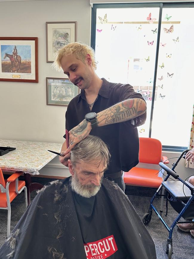 Evan Treacy, a local barber and co-owner of Thieves and Beggars, cutting Mater Private Hospital Rockhampton patient Noel Thompson's hair.