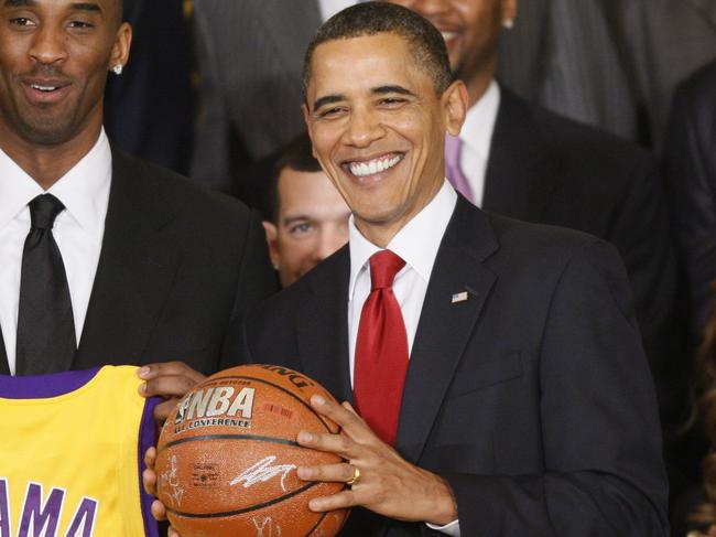 Los Angeles Lakers NBA guard Kobe Bryant with fellow Lakers players and luminaries including former team legend Magic Johnson (R), present US President Barack Obama an autographed basketball and personalized team jersey, as he welcomed the 2009 NBA champions in the East Room of the White House in Washington, DC 25/01/2010.