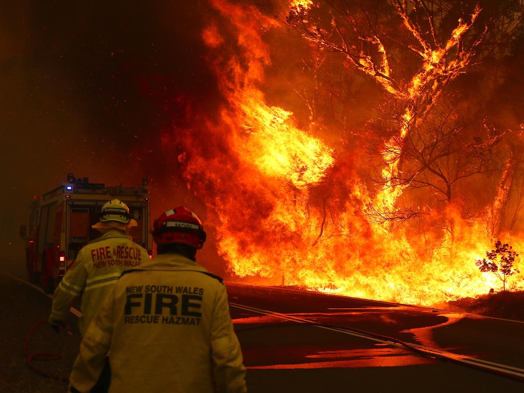 Fire and Rescue personal run to move their truck as a bushfire burns next to a major road and homes on the outskirts of the town of Bilpin on December 19, 2019 in Sydney, Australia. NSW Premier Gladys Berejiklian has declared a state of emergency for the next seven days with ongoing dangerous fire conditions and almost 100 bushfires burning across the state. It's the second state of emergency declared in NSW since the start of the bushfire season. (Photo by David Gray/Getty Images)