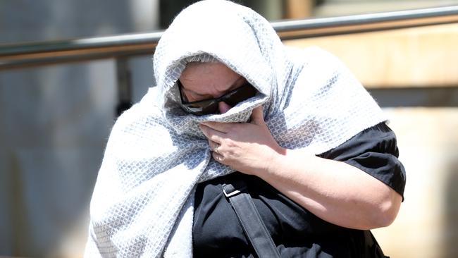 Fake nurse Helena Heaft covers her face as she leaves the Adelaide Magistrates Court in Adelaide, Friday, October 11, 2019. Picture: AAP / Kelly Barnes