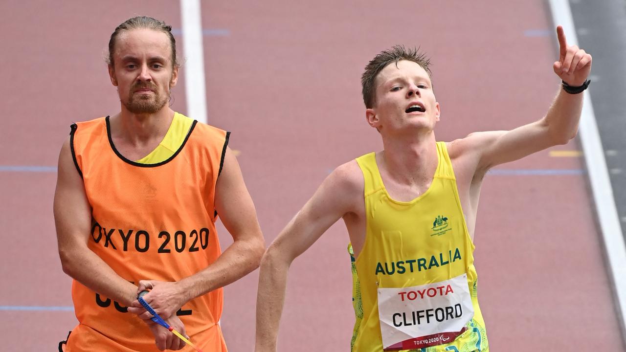 Australia's Jaryd Clifford (R) and his guide cross the finish line to win a silver medal in the men's marathon T12 event during the Tokyo 2020 Paralympic Games at the Olympic Stadium in Tokyo on September 5, 2021. (Photo by Kazuhiro NOGI / AFP)