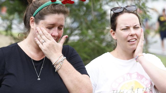 Shae Curr-Parkes and Kate Hammacott become distressed as they wait for word from family members stranded by flood waters at Holloways Beach. Picture: Brendan Radke