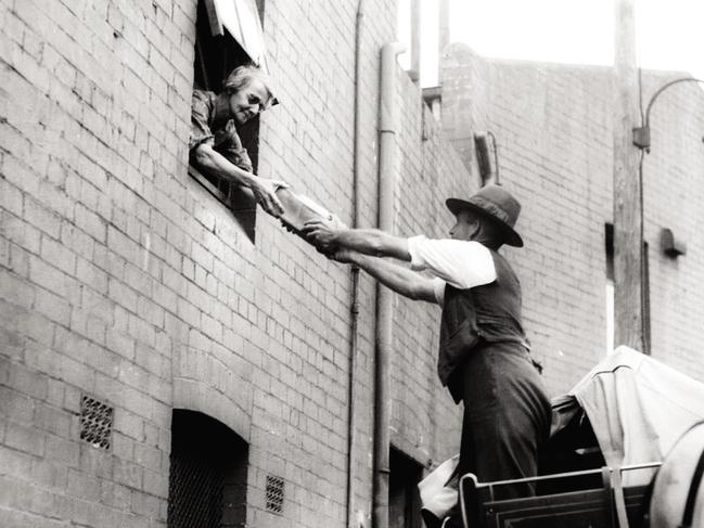 A bread delivery man hands up a loaf from his horse drawn cart to a woman in Sydney’s Potts Point during the Great Depression in 1935. From the book In Living Memory by Alasdair McGregor