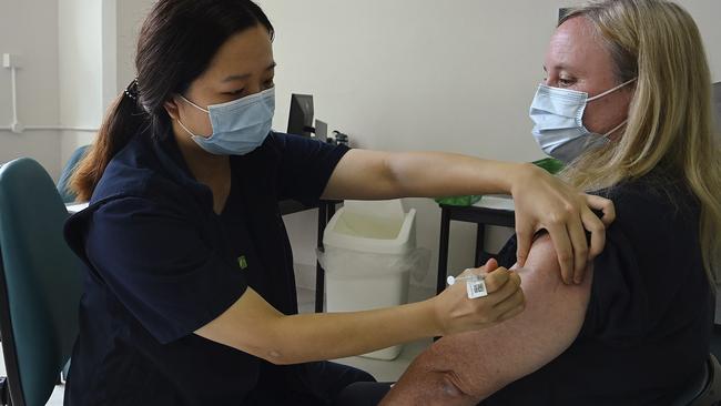 Nurse immuniser Zoe Leung (left) simulates administering a COVID-19 vaccine to Fiona Paine inside one of the vaccination rooms at the Sydney Local Health District Vaccination Hub. Picture: Kate Geraghty