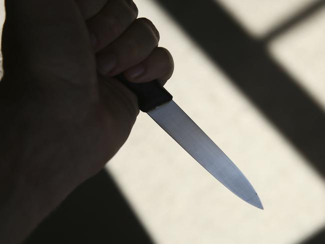 A hand holding a knife in shadow. This image can be used to represent stabbing or murder.