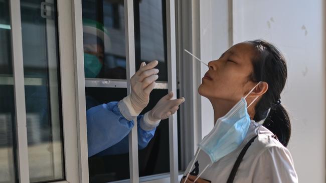 A medical worker takes a swab sample from a woman to test for COVID-19 in a hospital in Wuhan. Picture: Hector Retemal/AFP