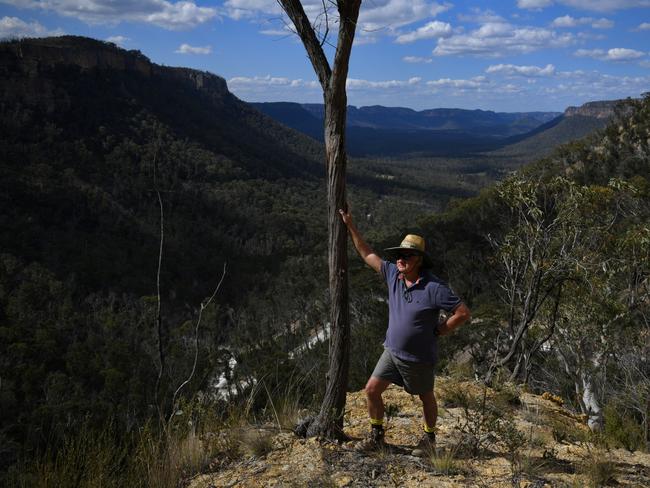 Wolgan Valley feature. Paul Vought stands atop the Donkey Steps, the colloquial name given to the new pass into the Wolgan Valley by locals. It was the original pass into the Valley when equipment was bought in in the late 1860s by donkey. Behind Paul is the Wolgan Valley. The old road  collapsed in on itself after the Black Summer Bushfires followed by a series of rain events  Photo: Dean Sewell / Oculi for the Australian